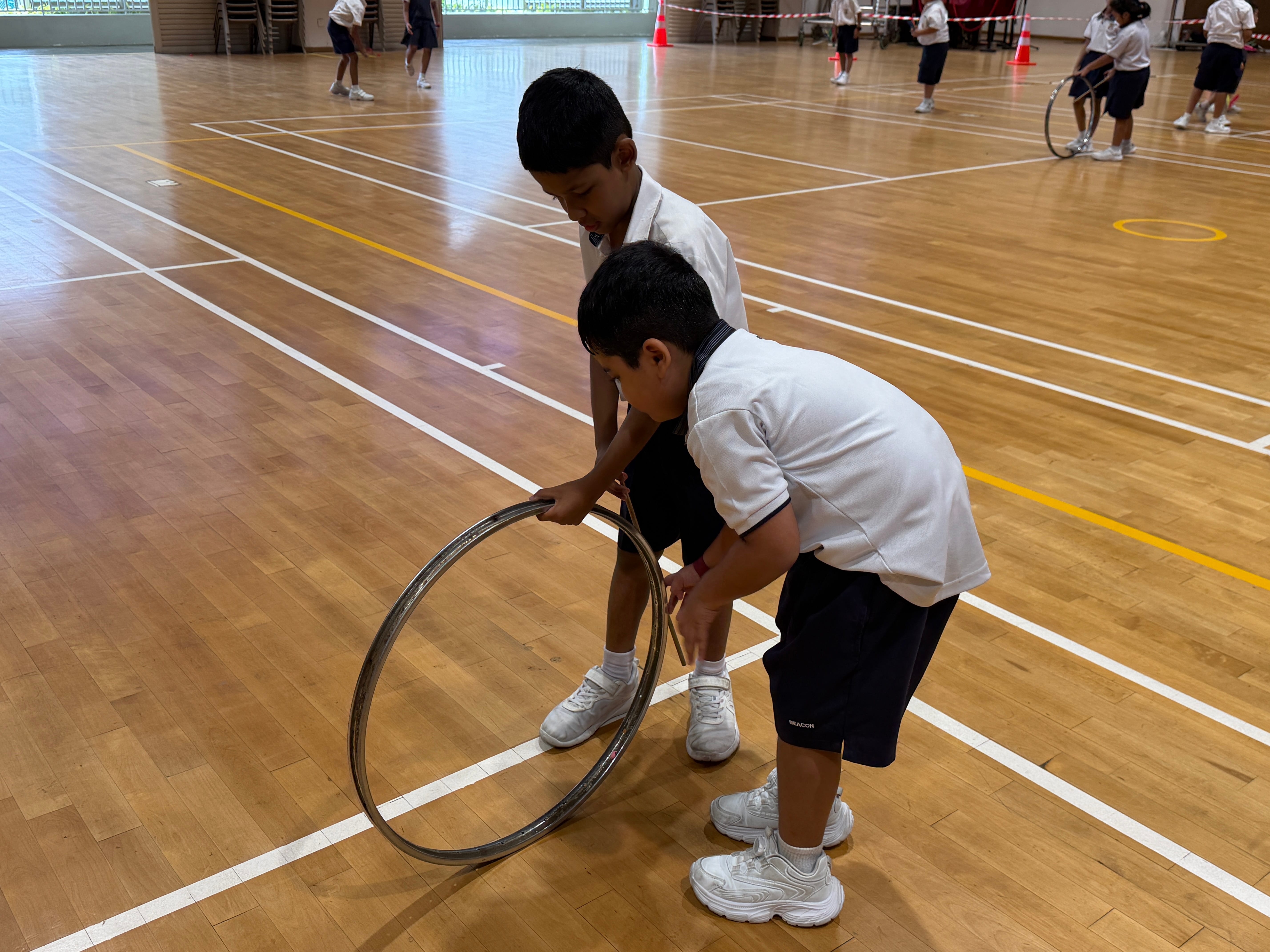 P1 ML students learning coordination and balance through the traditional Malay game of hoop rolling (main gelung).